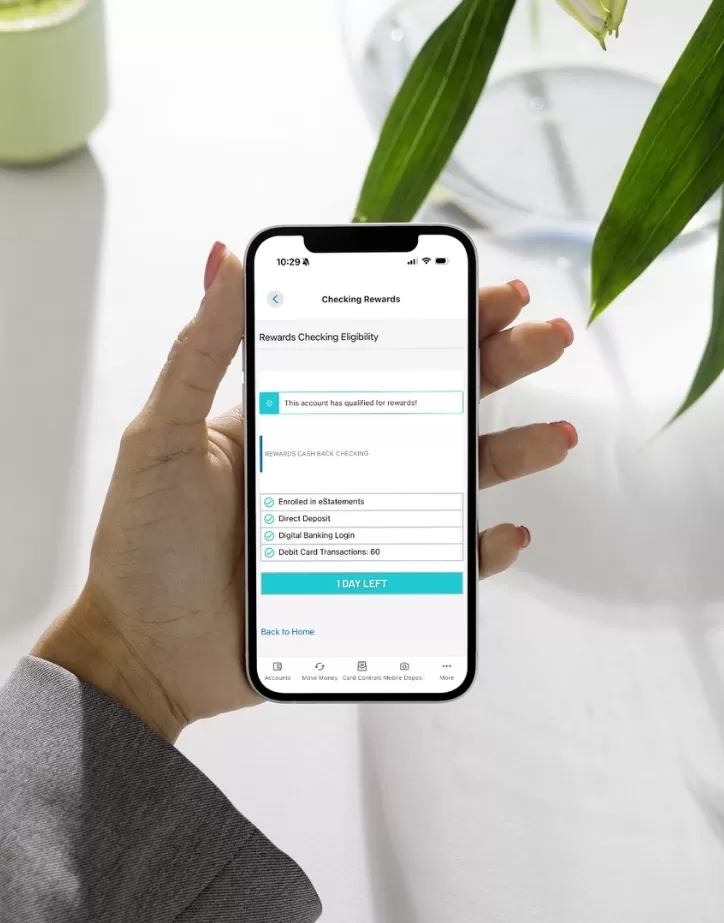 Women holding phone featuring the Rewards Checking Eligibility page in the Heritage Digital Banking App